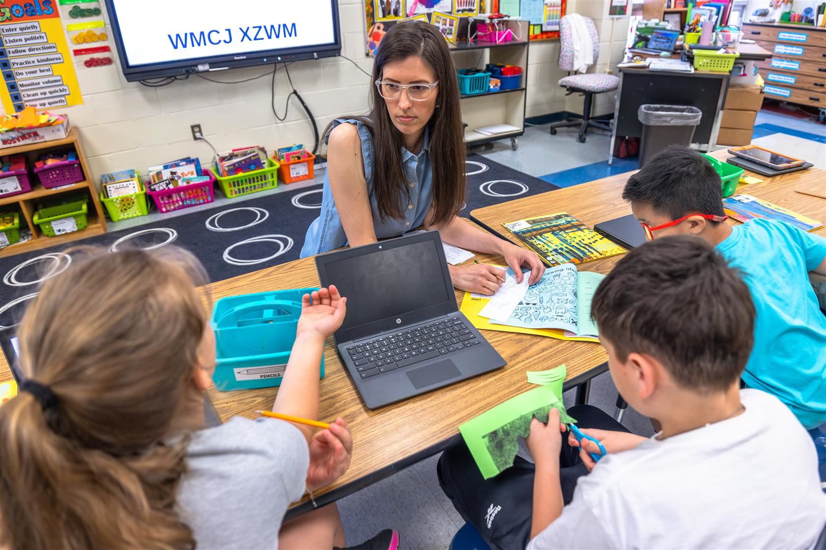 Guardrail 1 - Equity over Equality | Image of instructor at work station with students