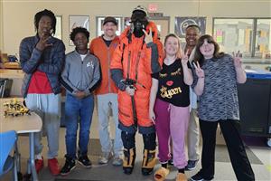 Students smiling in a picture with mountain climber