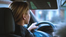  woman inside a car driving with her hands on the wheel. 