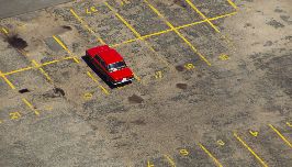  parking lot with one red car in a parking spot