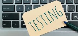  Computer keyboard with a post-it that says Testing