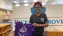 Hickory Grove Elementary media coordinator holds up her purple Girls on the Run shirt 