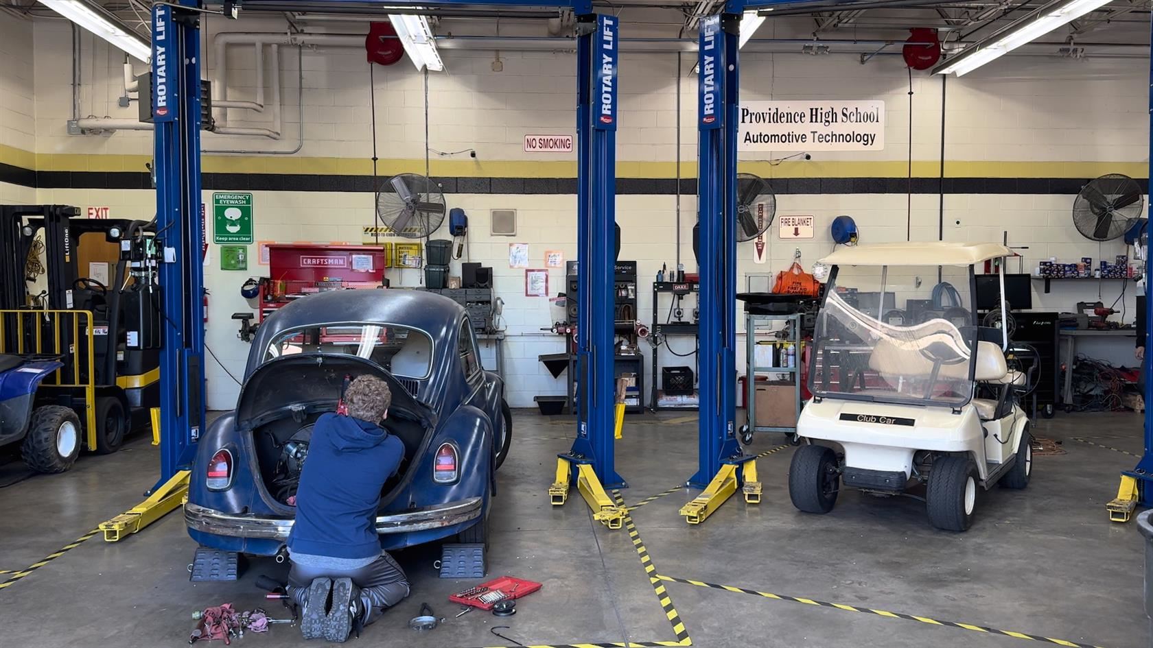  Providence High School student works under the hood of an old VW bug in automotive class