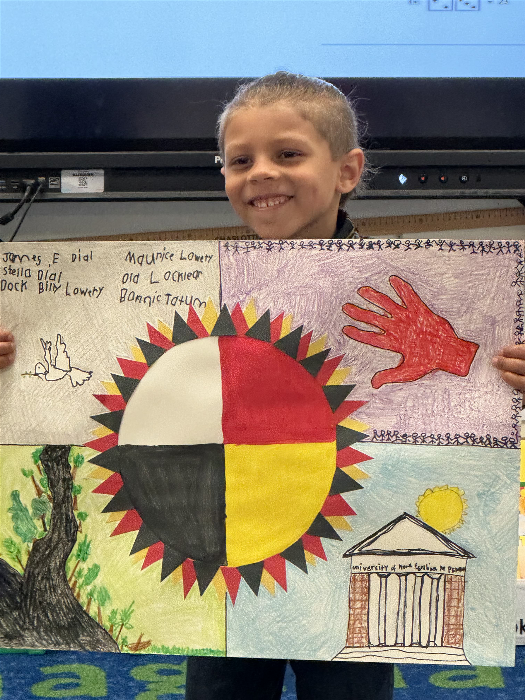 Kamden, student, stands in front of his classroom with his winning art project.