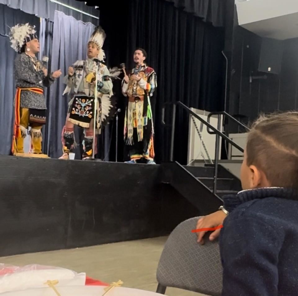Student watches Native American performers on stage.