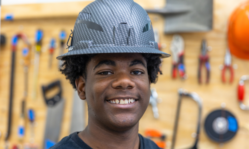  Headshot of Xavier Rhodes wearing a hardhat in front of a board of tools