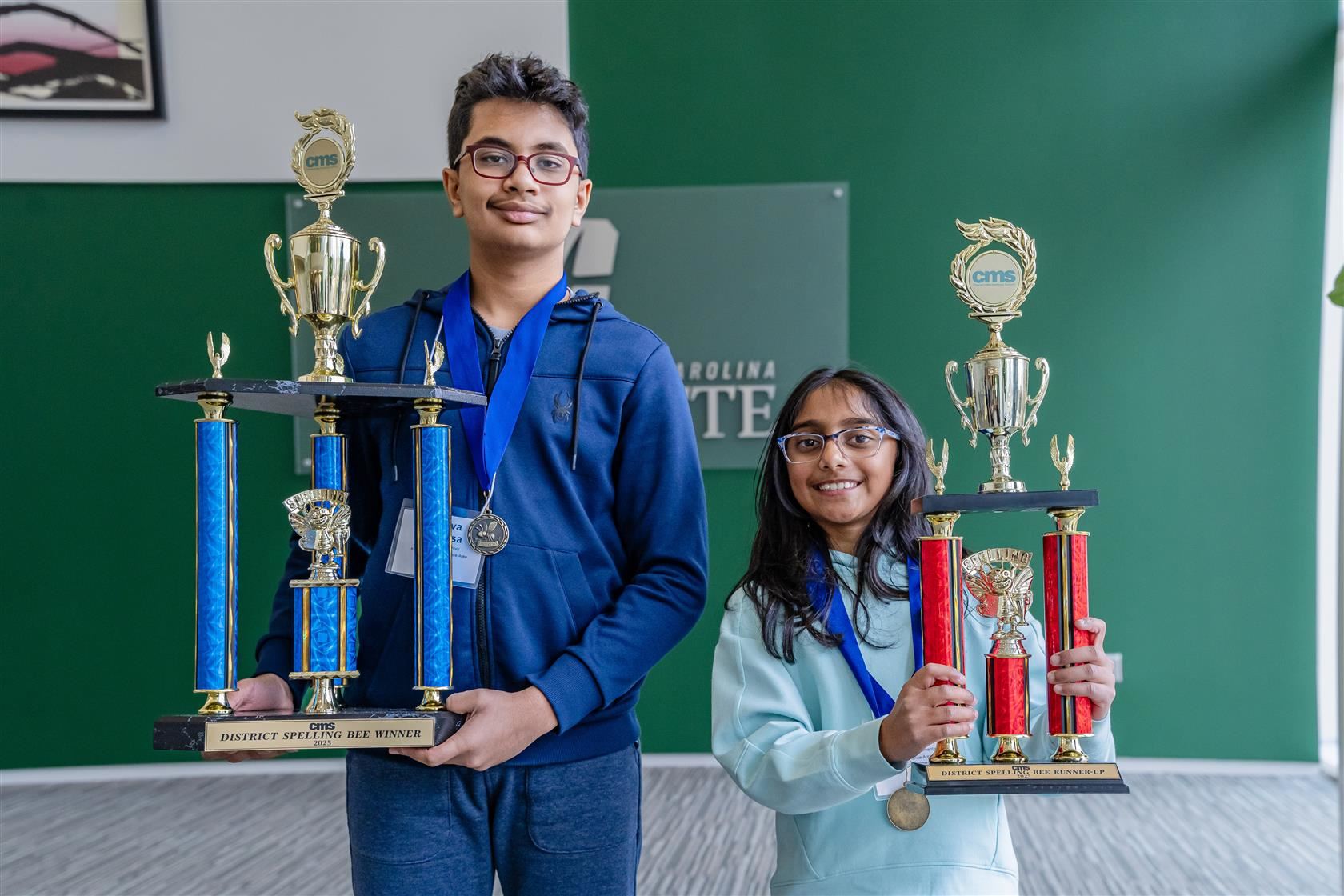 Dhruva Srivatsa (left) and Anika Ladde (right) smiling and holding their Spelling Bee trophies