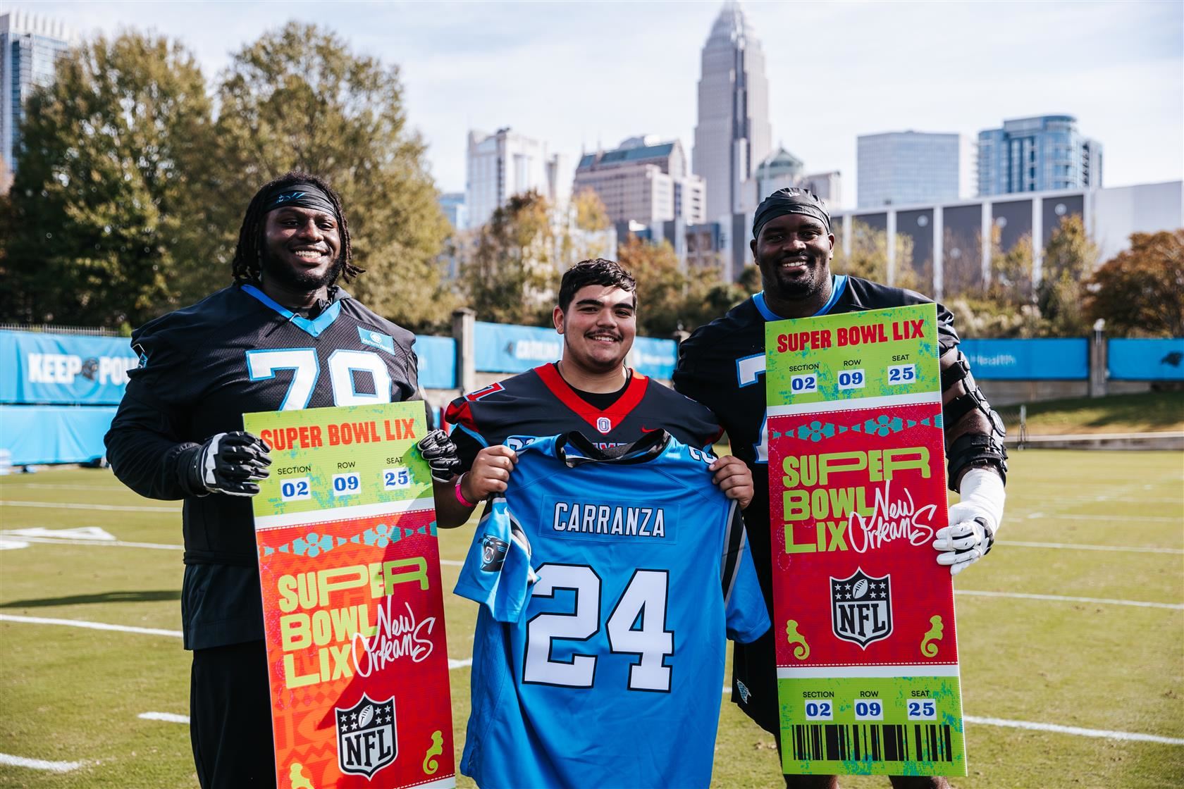 Olympic High School senior Lucas Carranza stands between two Carolina Panthers football players