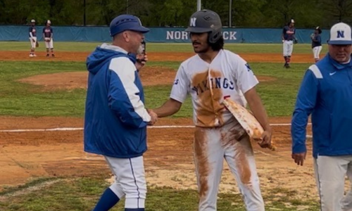  Ryan Clark (right) shakes hands with his coach while holding a base.