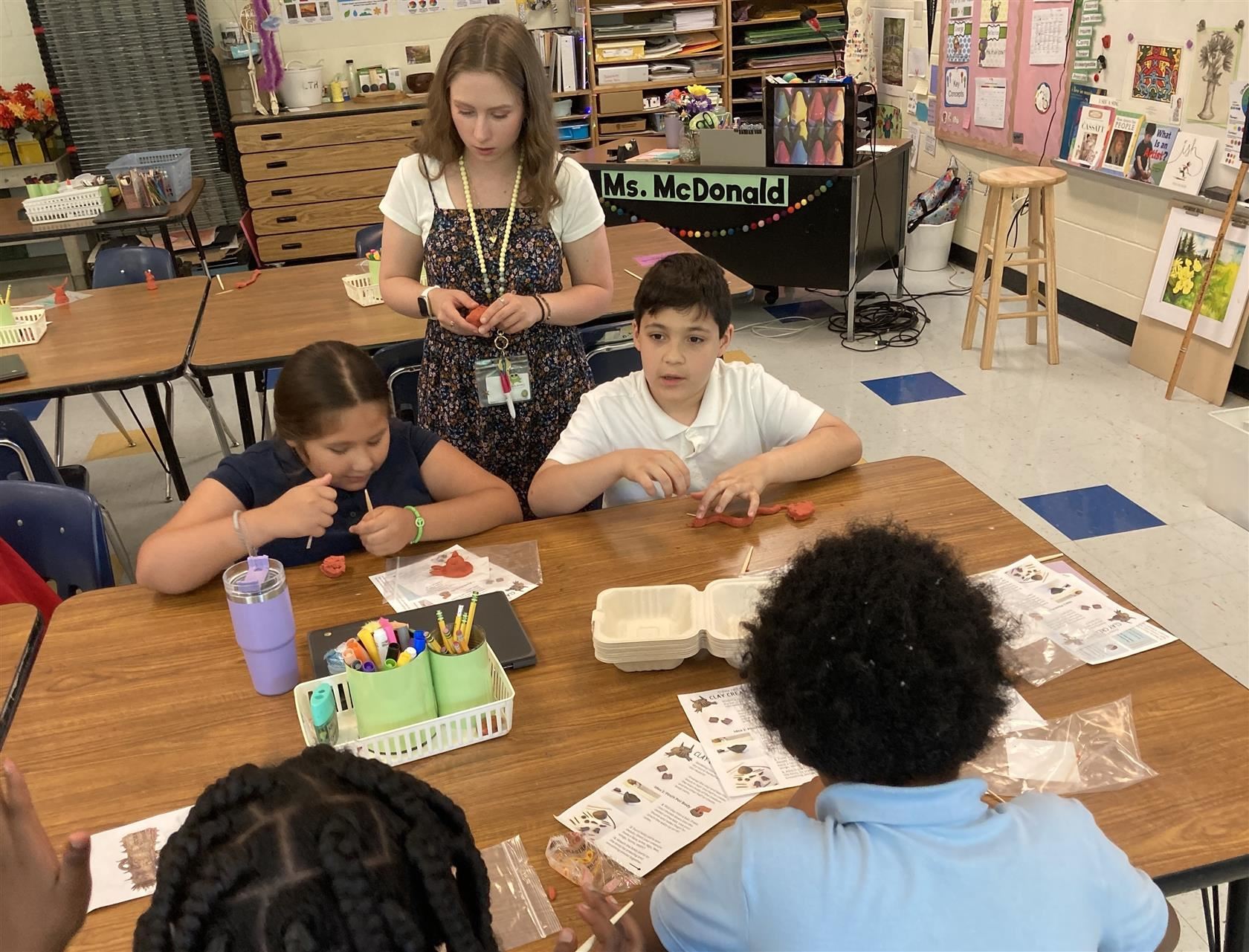 Katherine McDonald assisting students with their project at a table