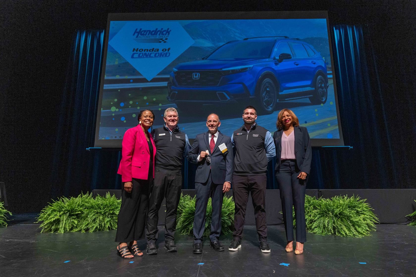 Gregory Gabriel (center) smiles alongside reps from Hendrick Automotive Group and CMS leaders