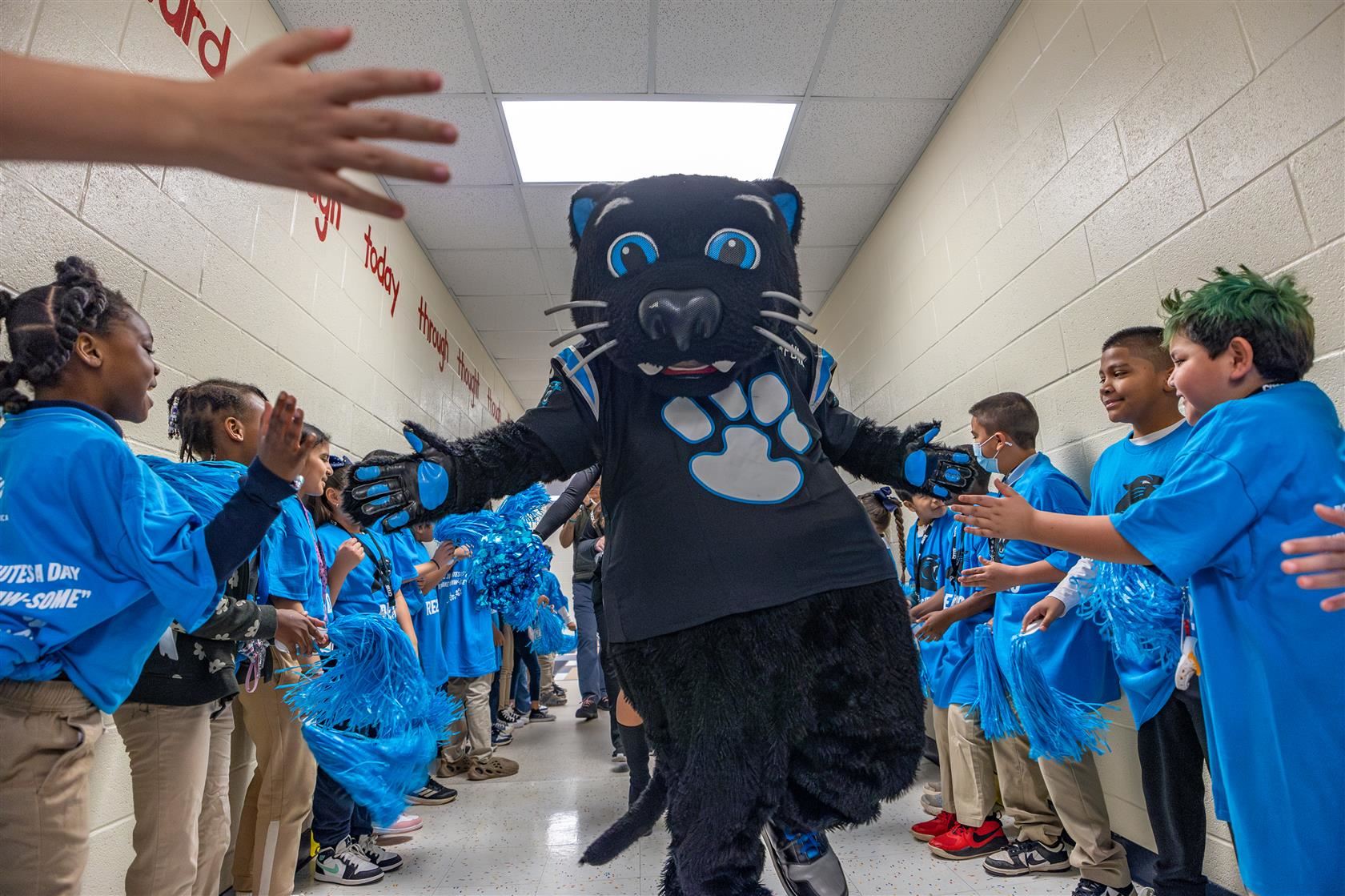 Sir Purr runs down the halls of MOIA while giving students high fives