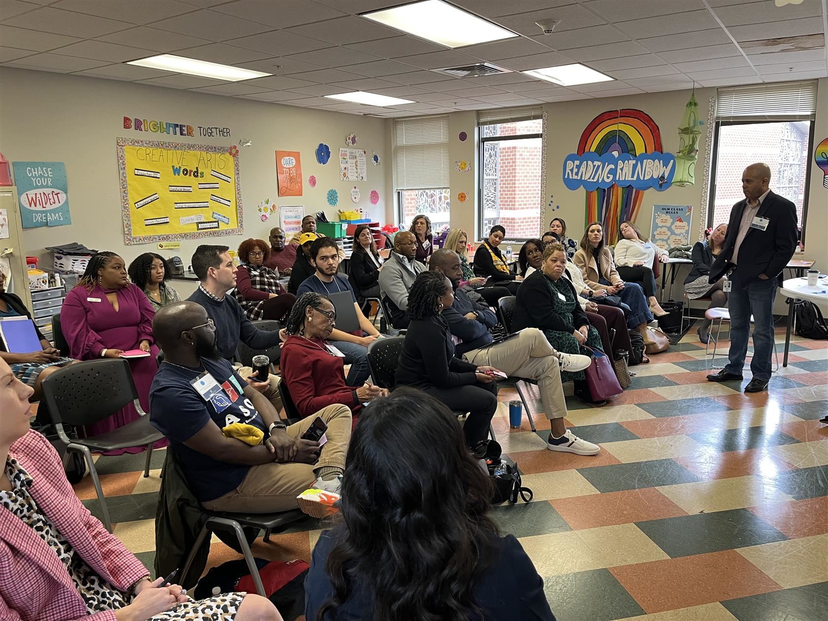 Several partner organization representatives sit in a classroom and share feedback on tutoring in the district.
