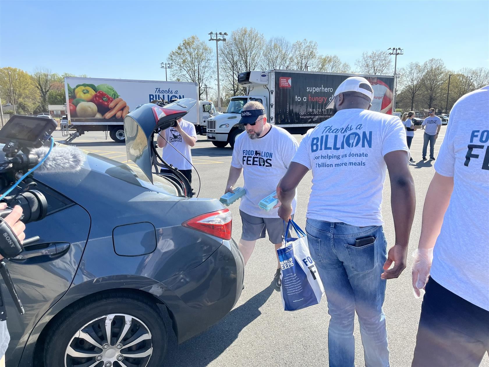 Volunteers pack produce in the trunk of a gray car