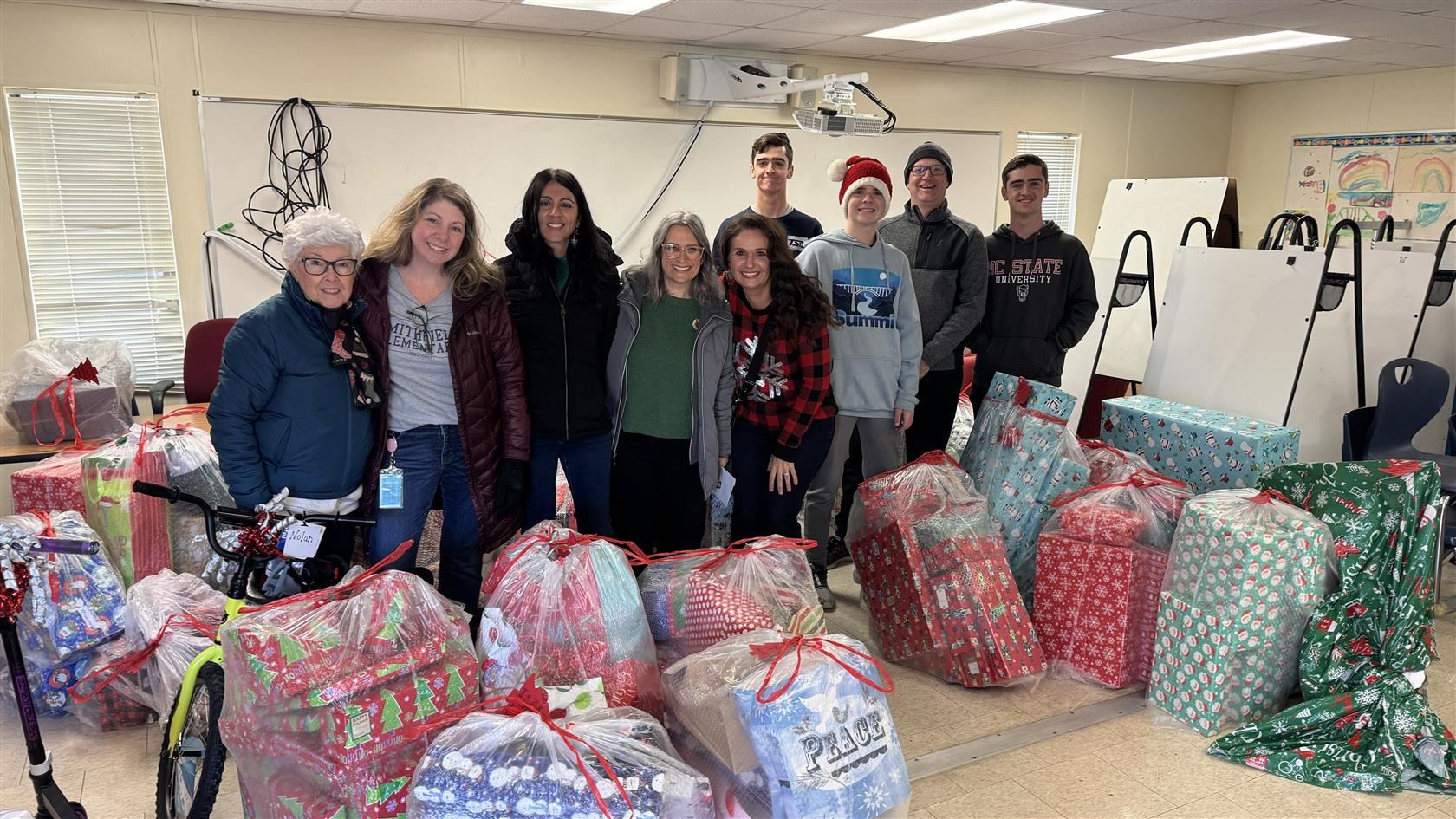 The Kilcoyne family and Smithfield Elementary staff stand in a trailer surrounded by gifts for the school's Angel Tree