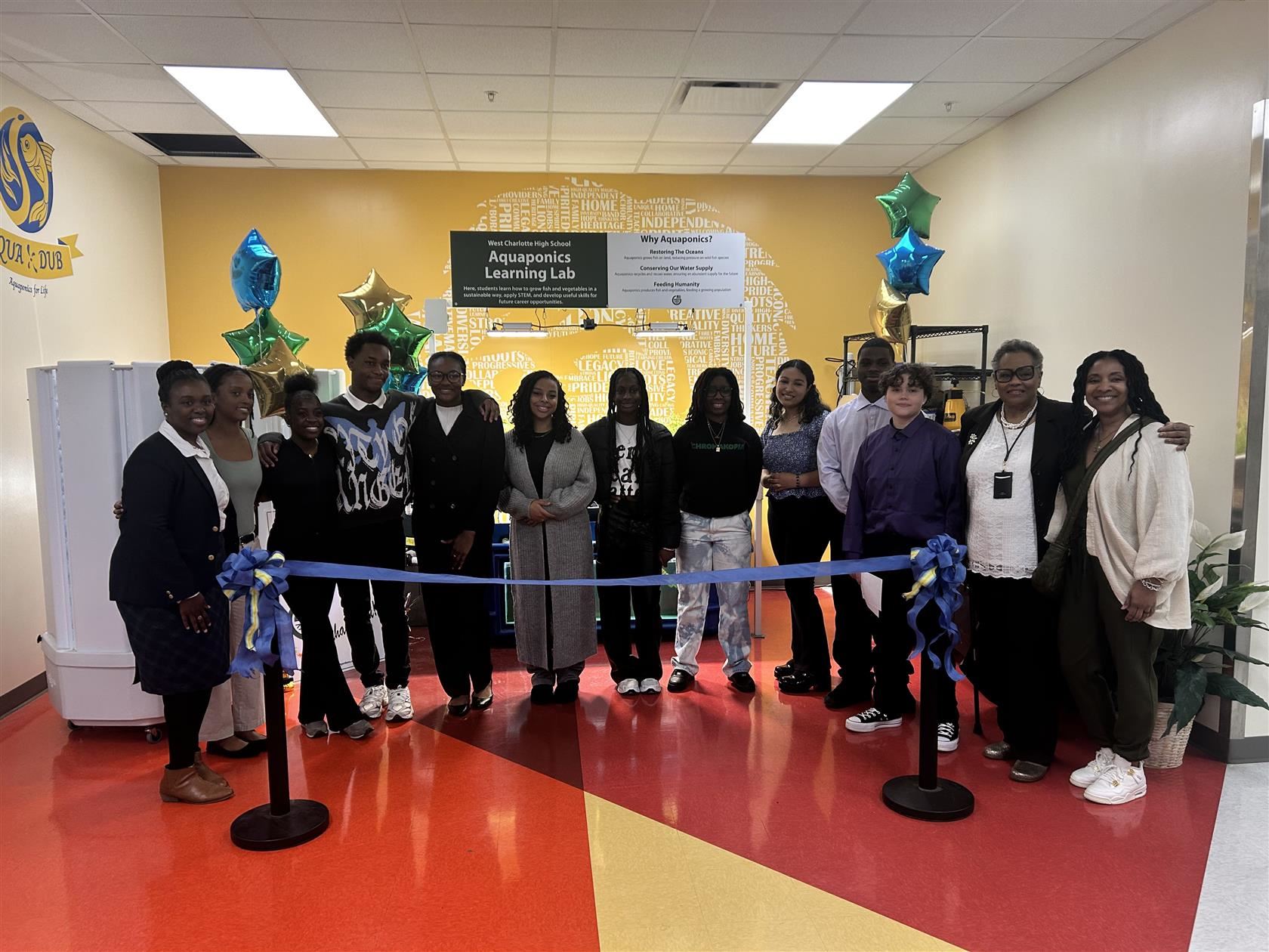 West Charlotte High students and staff stand behind a ceremonial ribbon to be cut for the new aquaponics system
