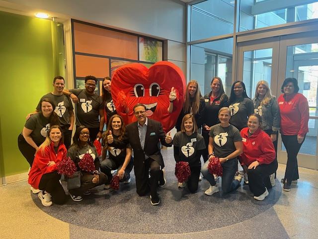 A group photo with the Red Heart mascot in the center.