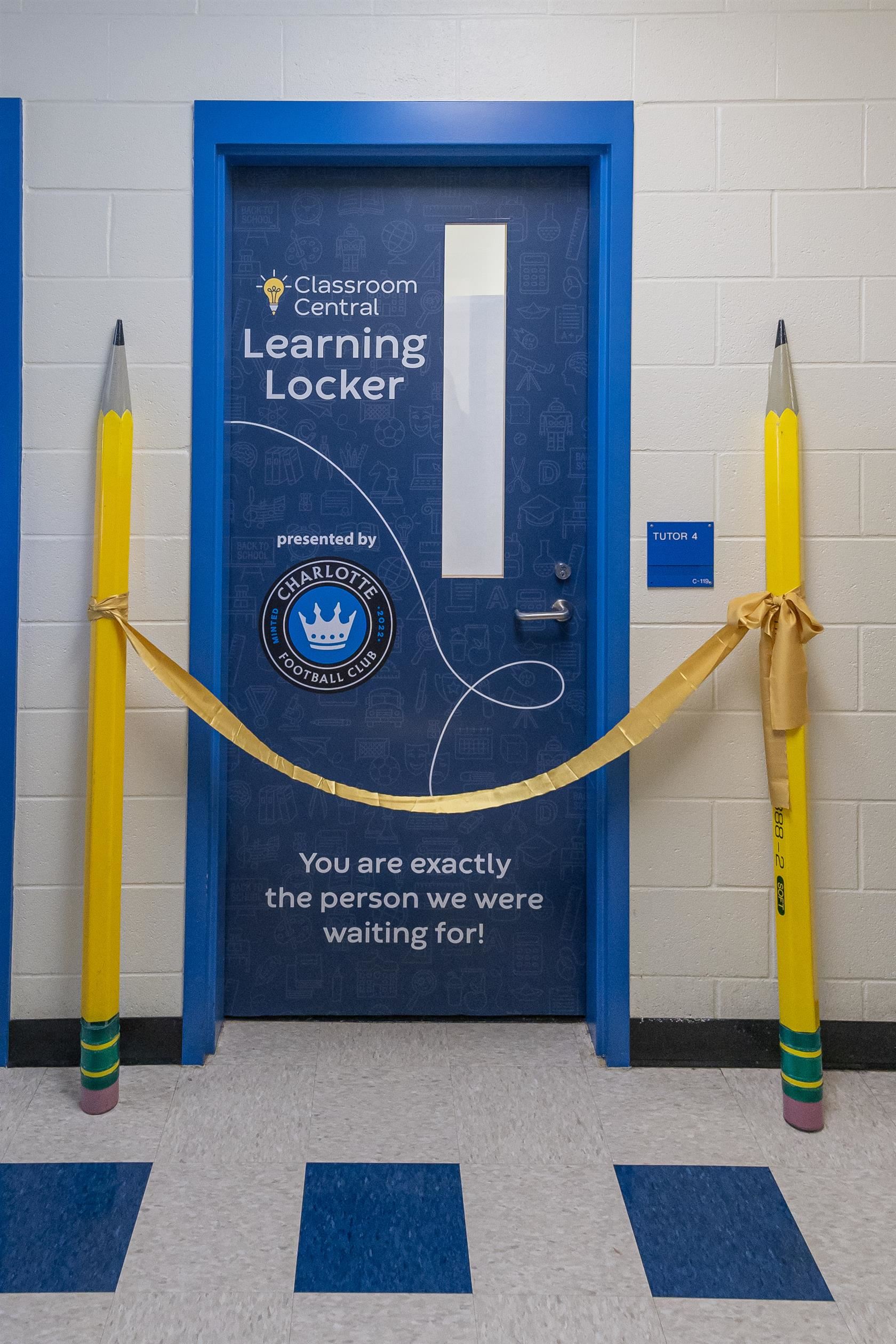 A ribbon with pencil stanchions is placed in front of a new Learning Locker at Nations Ford Elementary School