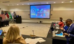 LaCaria updating the board on the first batch of projects in a room with a presentation on screen.